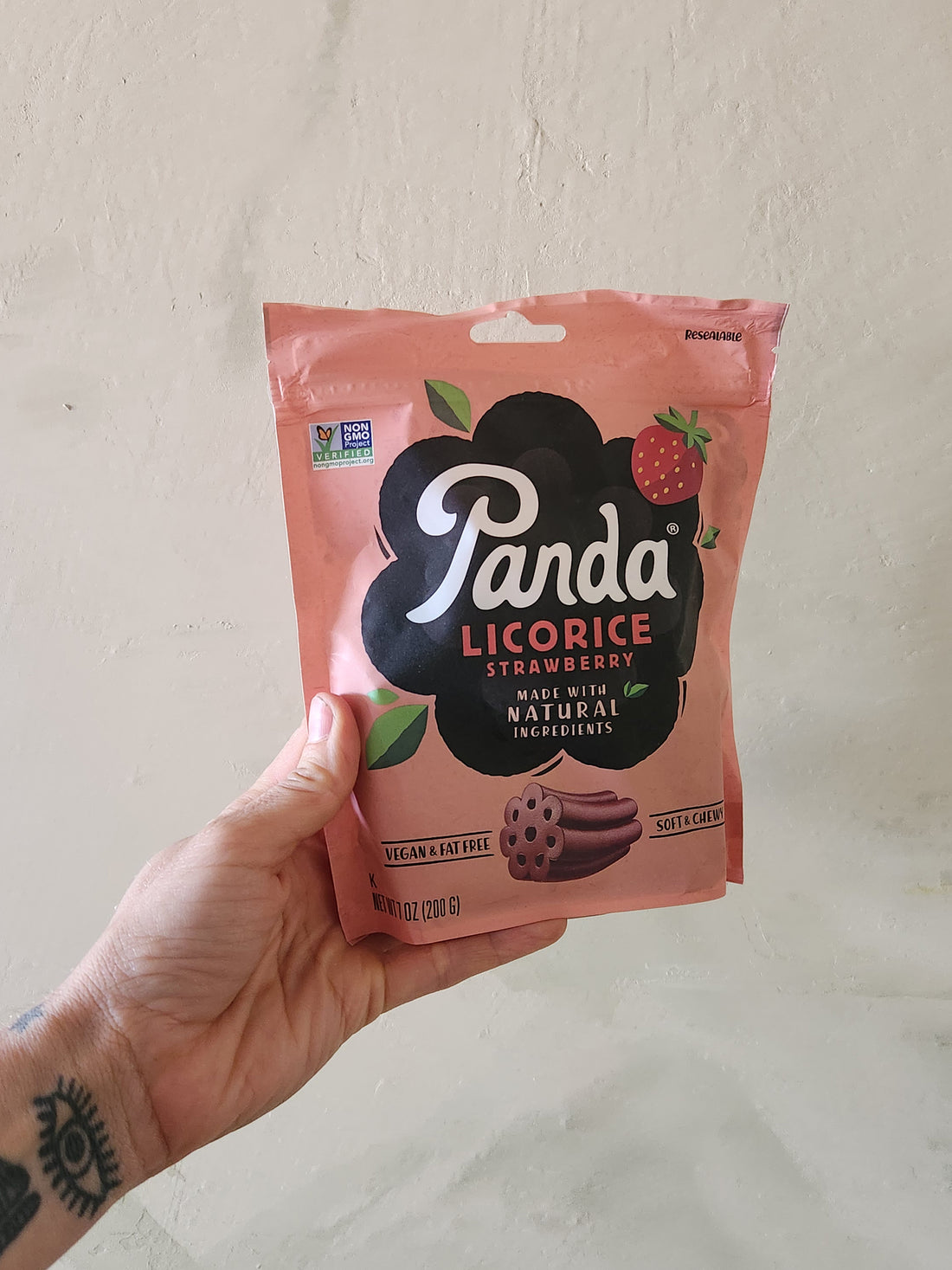 A hand holding a pouch of Strawbery licorice.