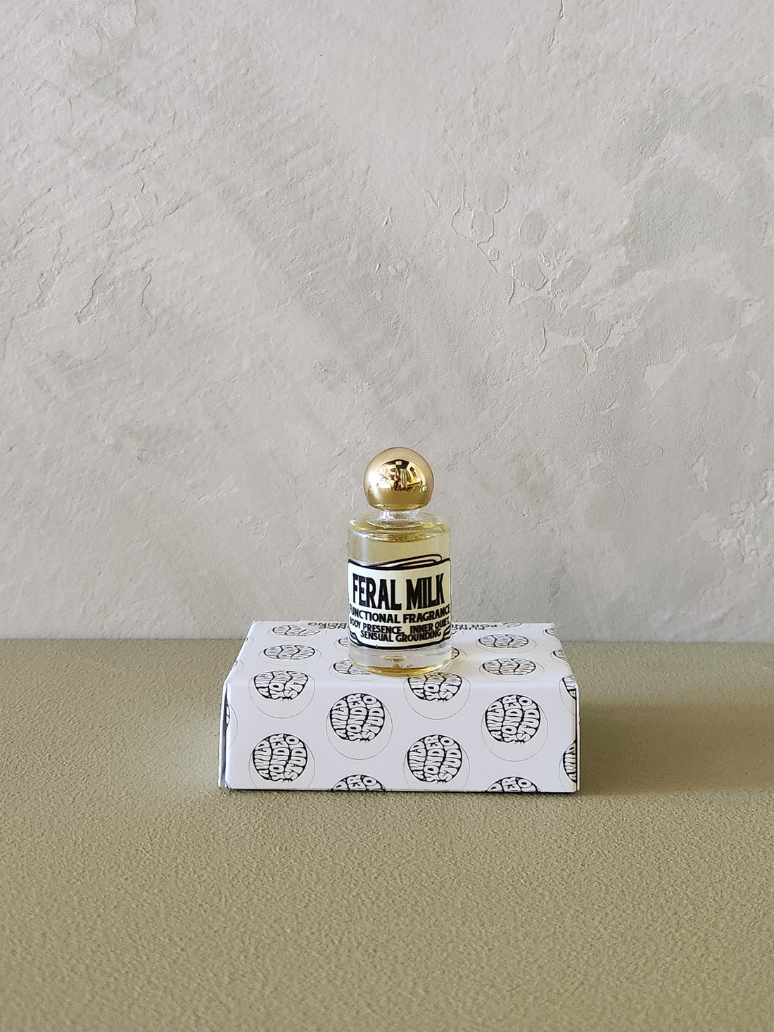 A small glass perfume bottle with a gold cap and a black-and-white label reading &