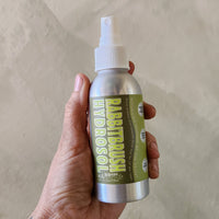 Hand holding a bottle of 'Rabbitbrush Hydrodual' with a beige background