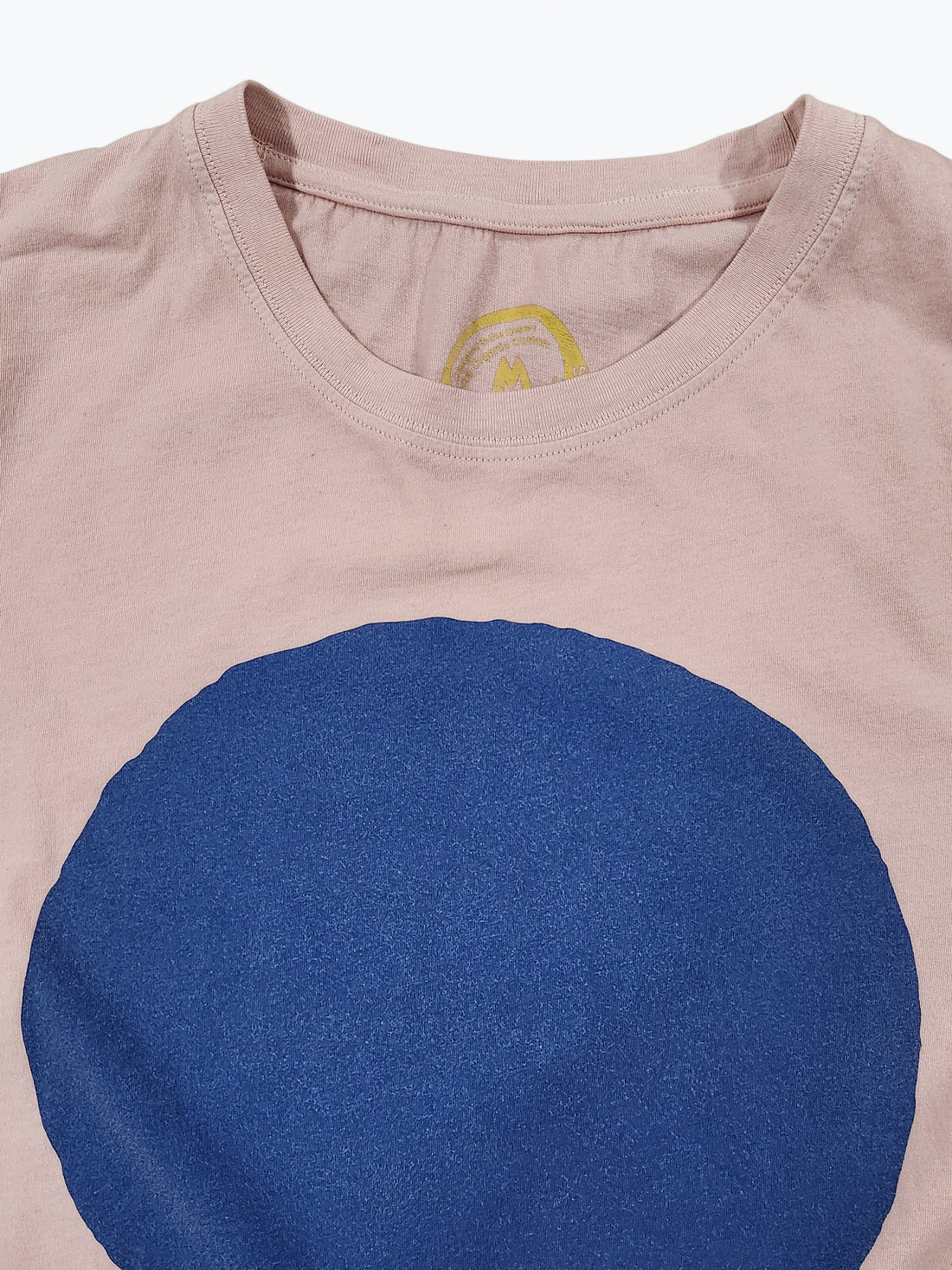 Pink t-shirt with a large blue circle and a small yellow logo on a white background