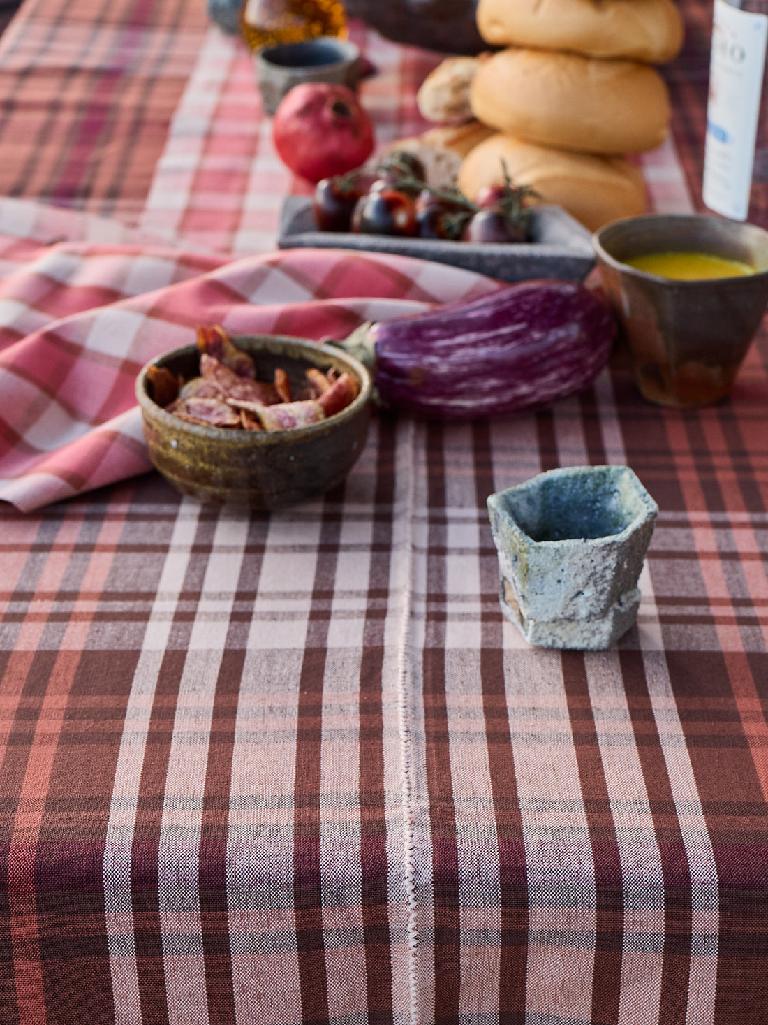 Table setting with checkered tablecloth, bowls, and fruits on a rustic background