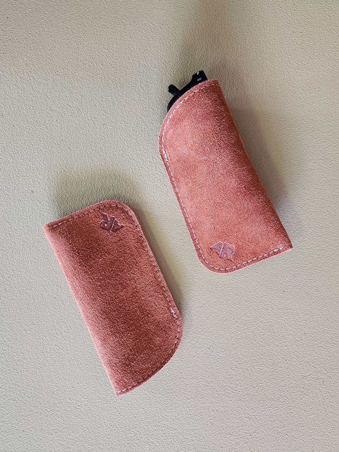 Two rust suede eyeglass cases on a light gray background