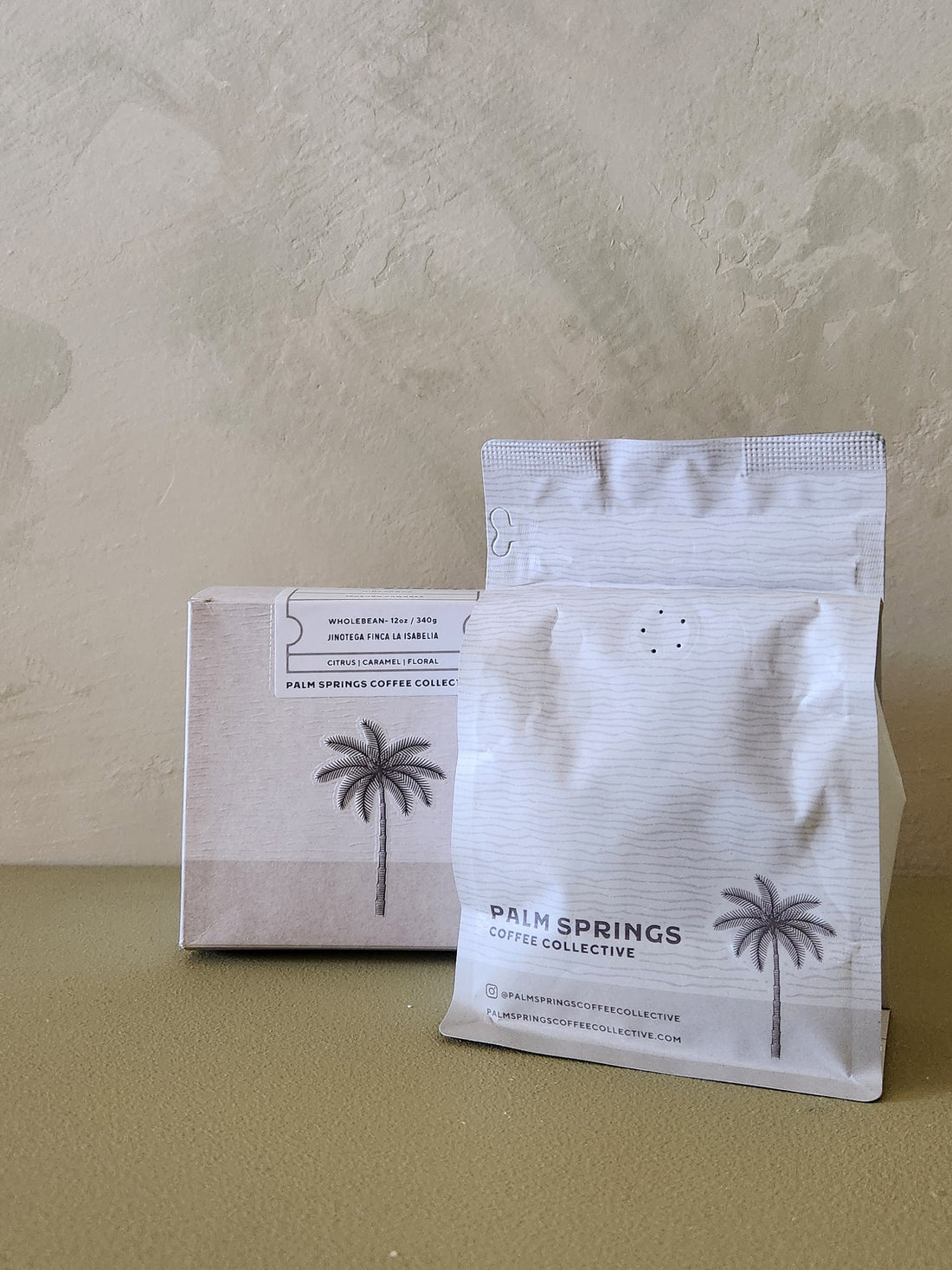 Two coffee packages from Pain Springs Coffee Collective on a neutral background