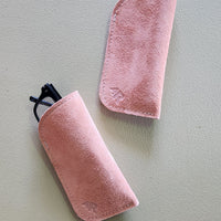 Two tan suede eyeglass cases on a light gray background