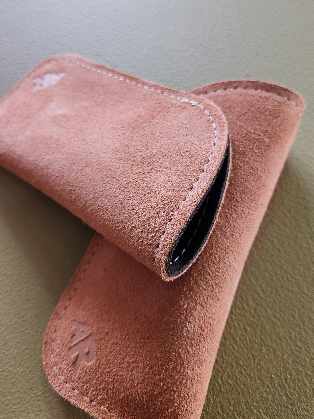 tan suede eyeglass case on a green surface