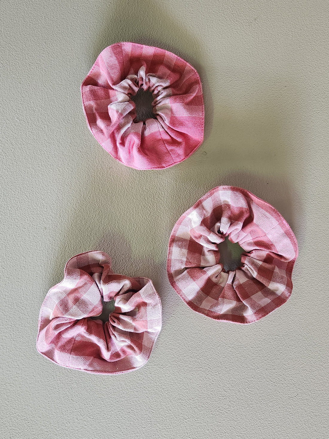 Three pink fabric flowers on a light gray background