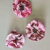 Three pink fabric flowers on a light gray background