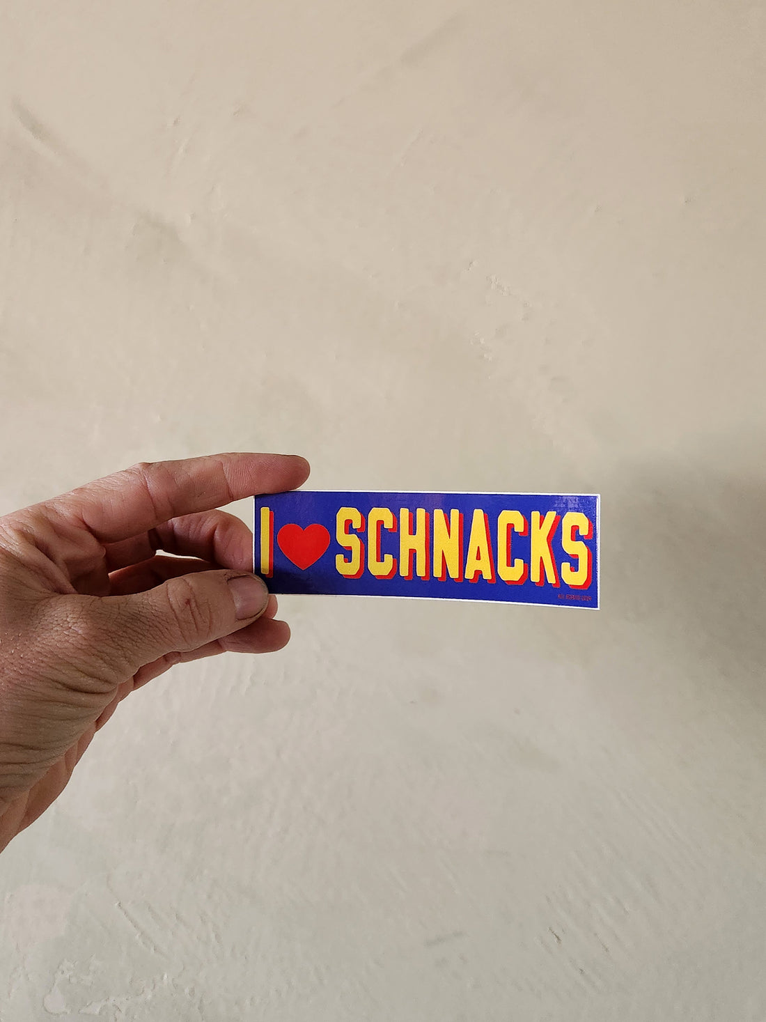 Hand holding a rectangular sticker with &