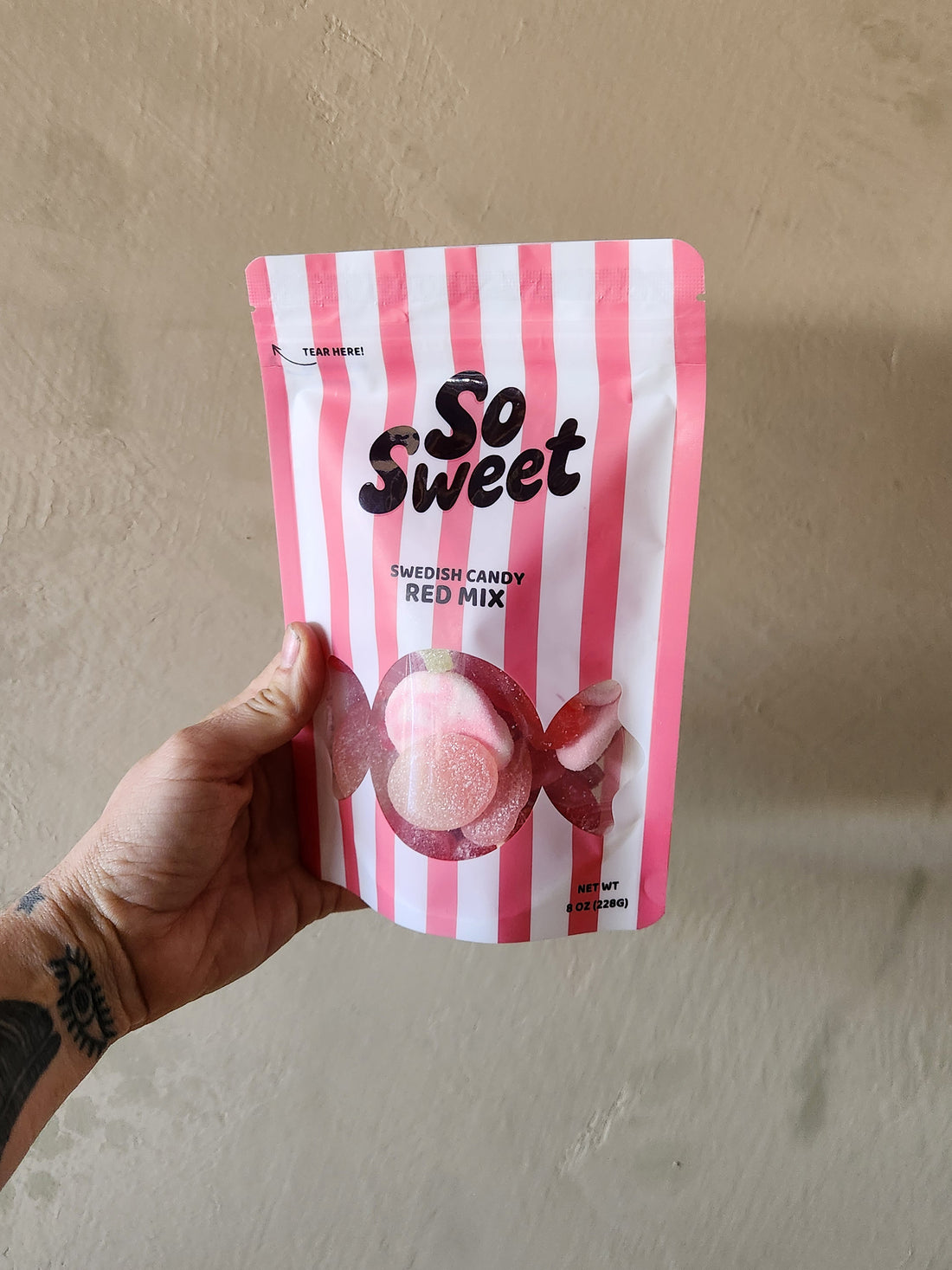 Hand holding a pink and white striped bag labeled &