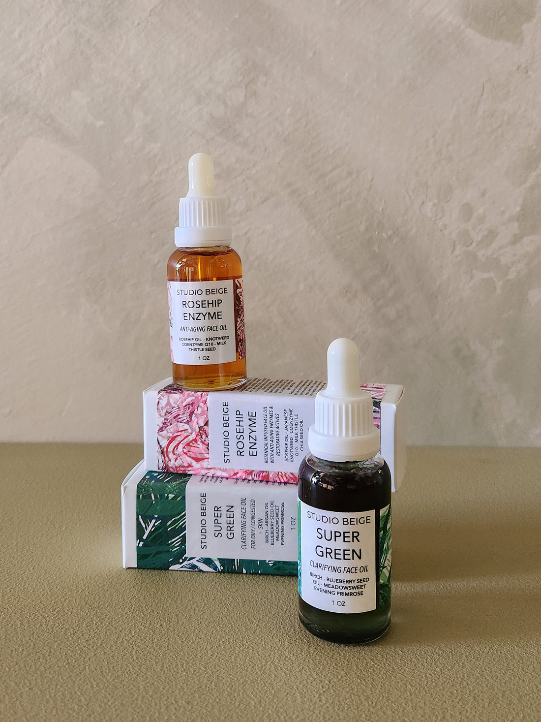 Two bottles of facial oils with their packaging on a neutral background