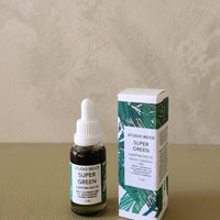 Bottle and box of Studio Beige Super Green face oil on a beige surface with a neutral background