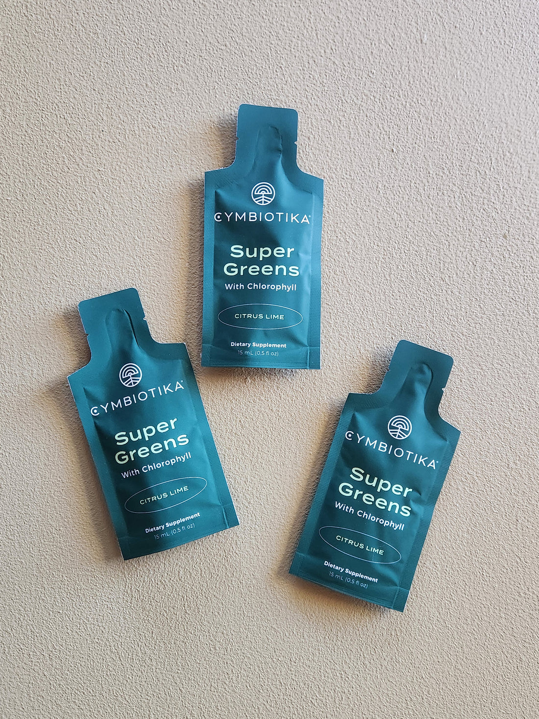 Three packets of Gymbiotika Super Greens on a light gray background