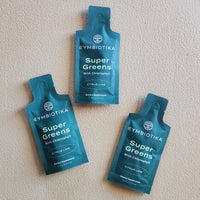 Three packets of Gymbiotika Super Greens on a light gray background