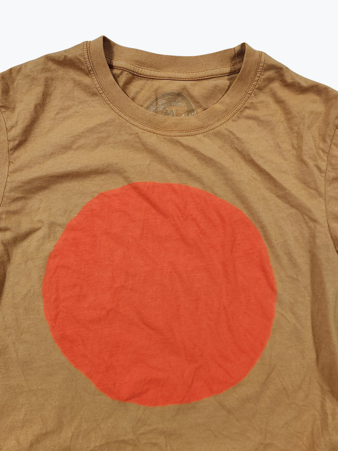 Ochre t-shirt with a large orange circle on a beige background