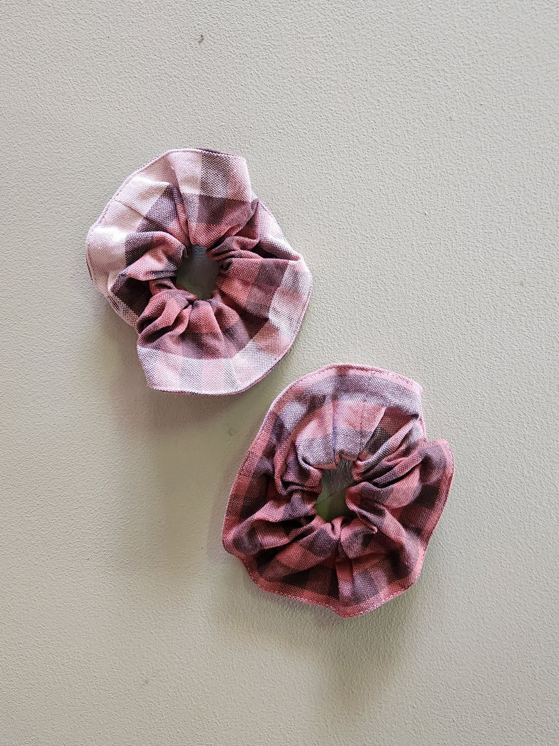 Two pink plaid scrunchies on a light gray background