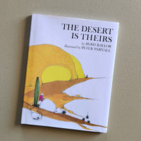 Book titled 'The Desert is Theirs' on a beige background