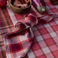 Plaid napkin on a checkered tablecloth with vegetables and a bowl.