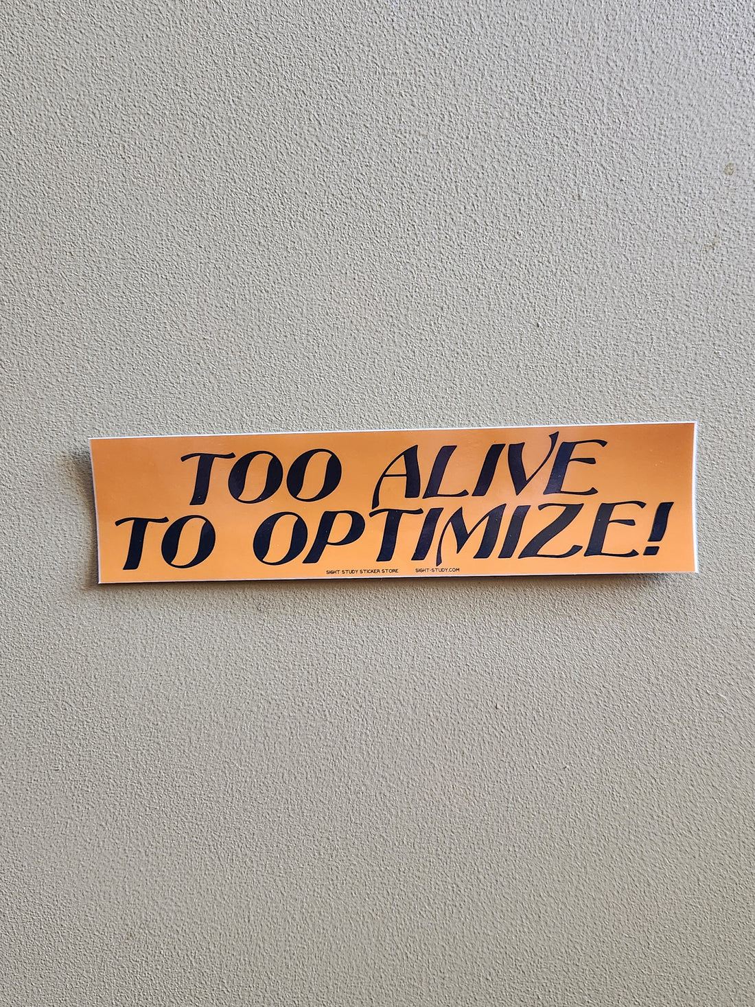 An orange rectangular bumper sticker with the text &