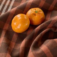 Two mandarins on a brown checkered fabric