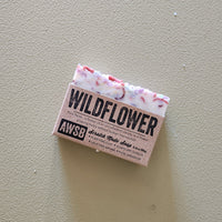 Bar of soap with 'Wildflower' and 'AWSB' branding on a beige background